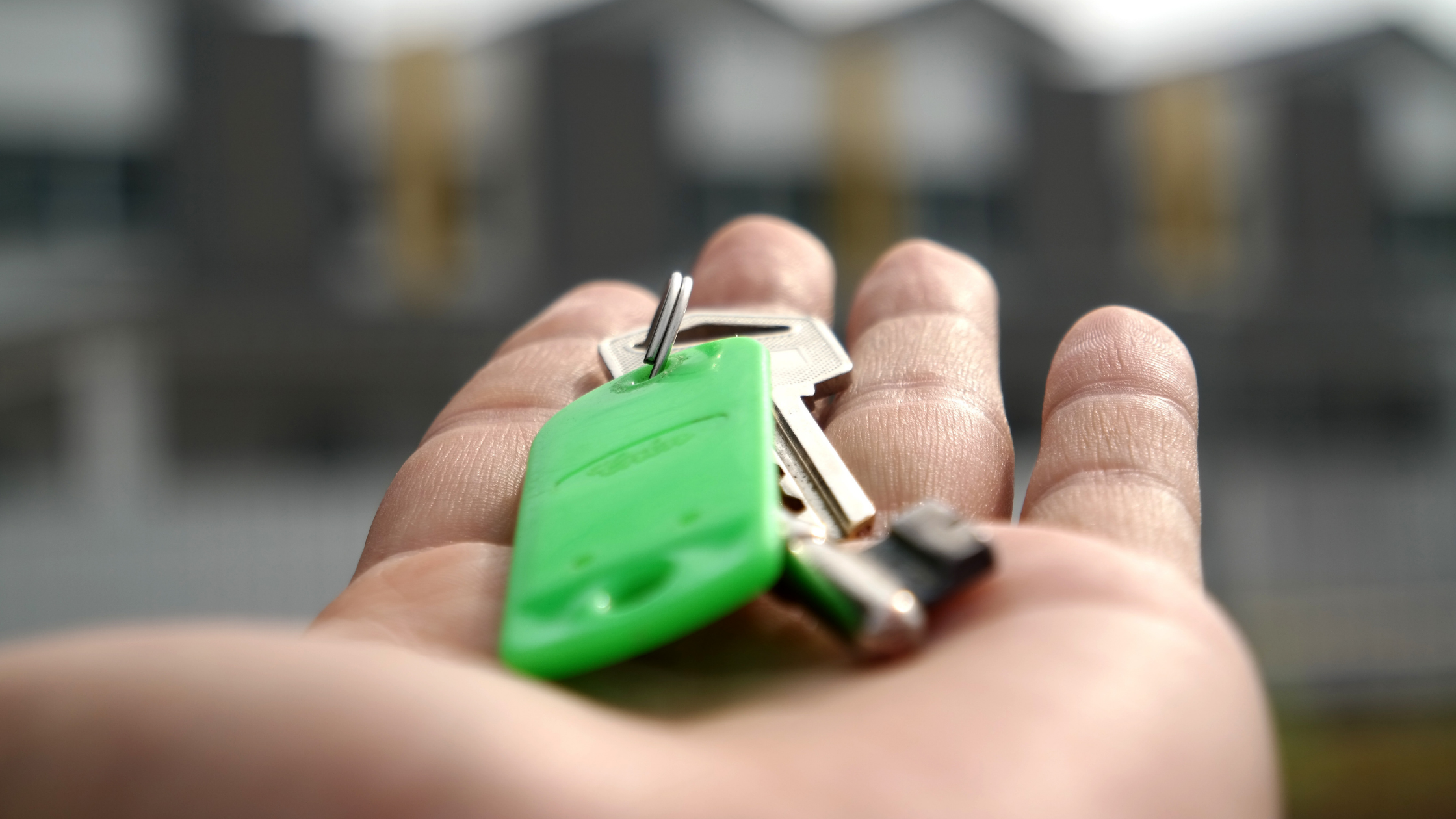 Person holding a set of keys to a house in their outstretched hand.